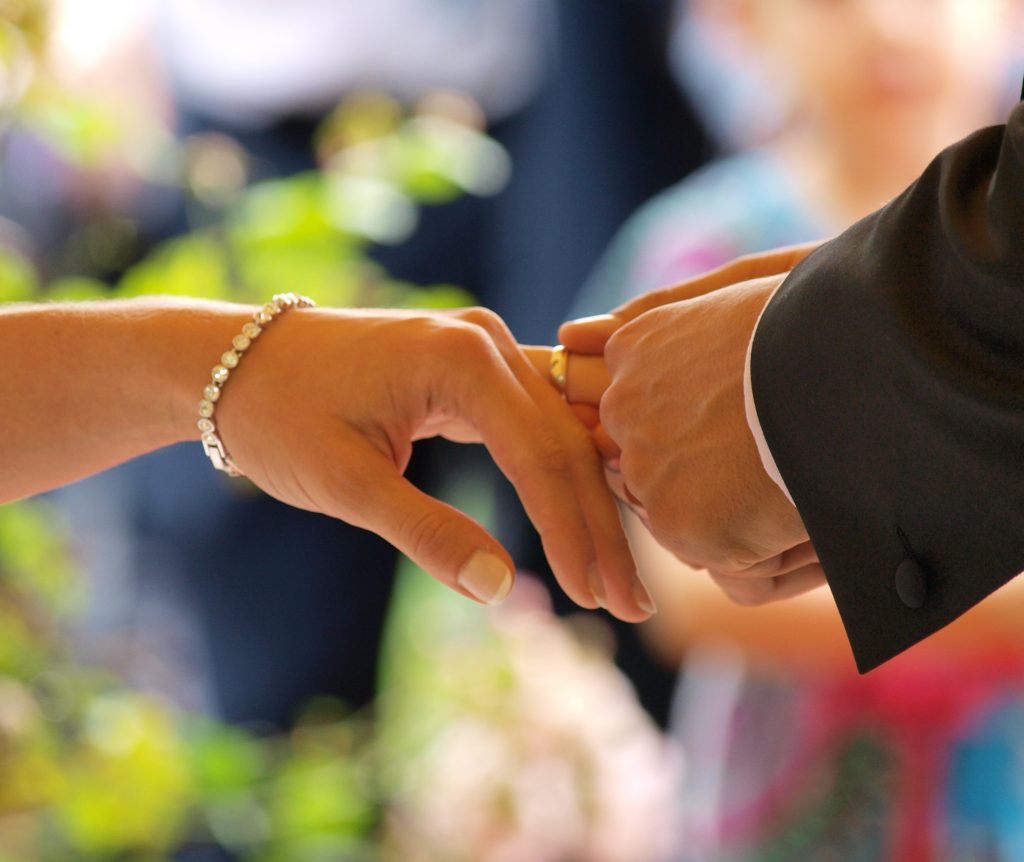 Groom placing wedding ring in the finger of bride